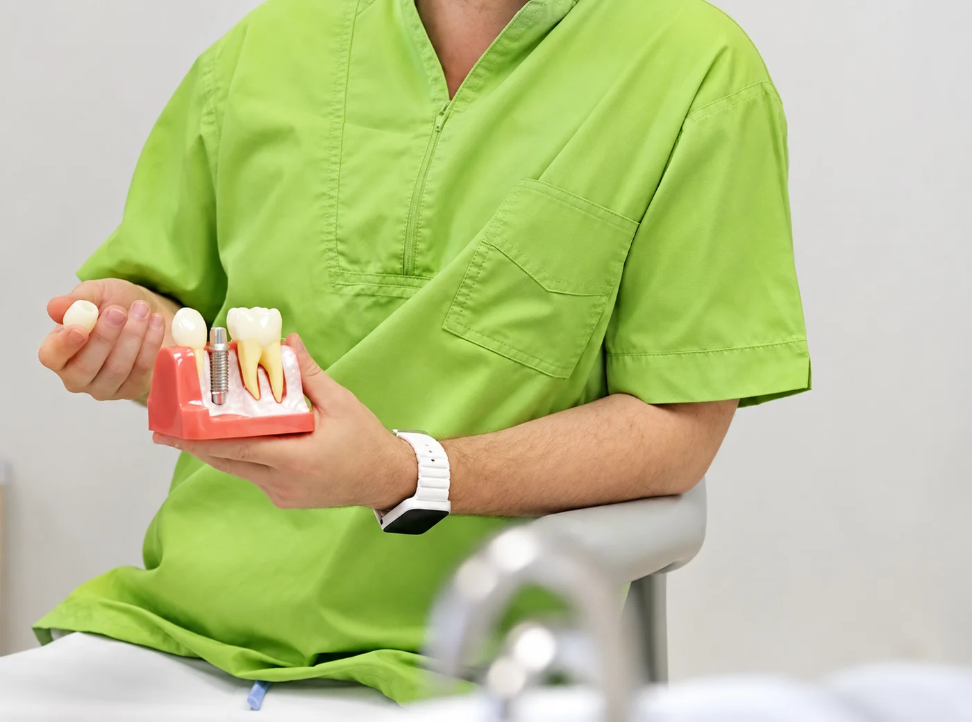 Lekarz LumiDent pokazuje na modelu ząb, implant i koronę